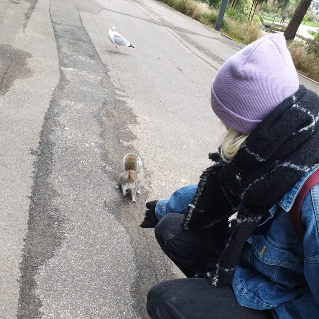 Lune holding their gloved hand out to a squirrel.
